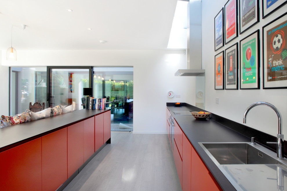 Inspiration for a large contemporary galley dark wood floor open concept kitchen remodel in Hertfordshire with flat-panel cabinets, orange cabinets, blue backsplash, glass sheet backsplash, stainless steel appliances, a drop-in sink, quartzite countertops and an island