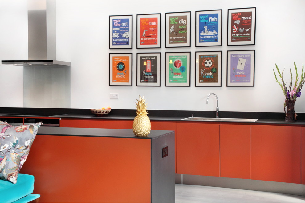 Offene, Zweizeilige, Große Moderne Küche mit flächenbündigen Schrankfronten, orangefarbenen Schränken, Küchenrückwand in Blau, Glasrückwand, Küchengeräten aus Edelstahl, Einbauwaschbecken, Quarzit-Arbeitsplatte, dunklem Holzboden und Kücheninsel in Hertfordshire