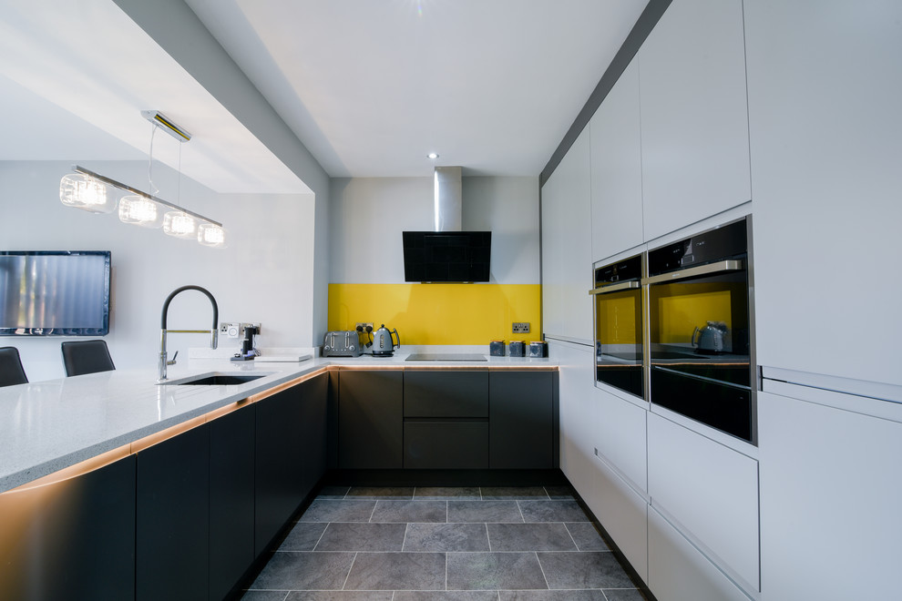 Exempel på ett mellanstort modernt grå grått kök, med släta luckor, grå skåp, bänkskiva i kvartsit, gult stänkskydd, glaspanel som stänkskydd, integrerade vitvaror och grått golv