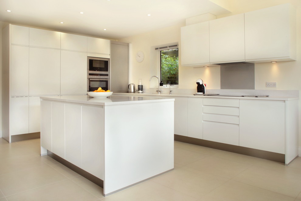 Inspiration for a large contemporary l-shaped open plan kitchen in Buckinghamshire with an integrated sink, flat-panel cabinets, white cabinets, quartz worktops, grey splashback, glass sheet splashback, stainless steel appliances, porcelain flooring and an island.