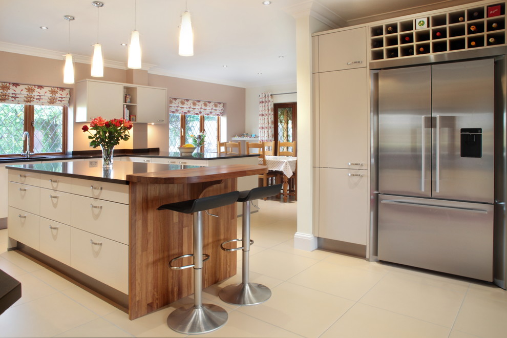 Large contemporary u-shaped kitchen/diner in Buckinghamshire with flat-panel cabinets, beige cabinets, quartz worktops, red splashback, glass sheet splashback, porcelain flooring, an island, a submerged sink and stainless steel appliances.