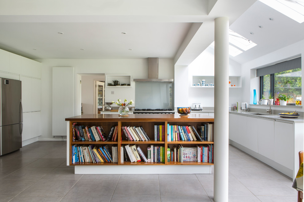 Mittelgroße Moderne Wohnküche in L-Form mit flächenbündigen Schrankfronten, weißen Schränken, Mineralwerkstoff-Arbeitsplatte, Kücheninsel, Unterbauwaschbecken, Glasrückwand, Küchengeräten aus Edelstahl und grauem Boden in Oxfordshire