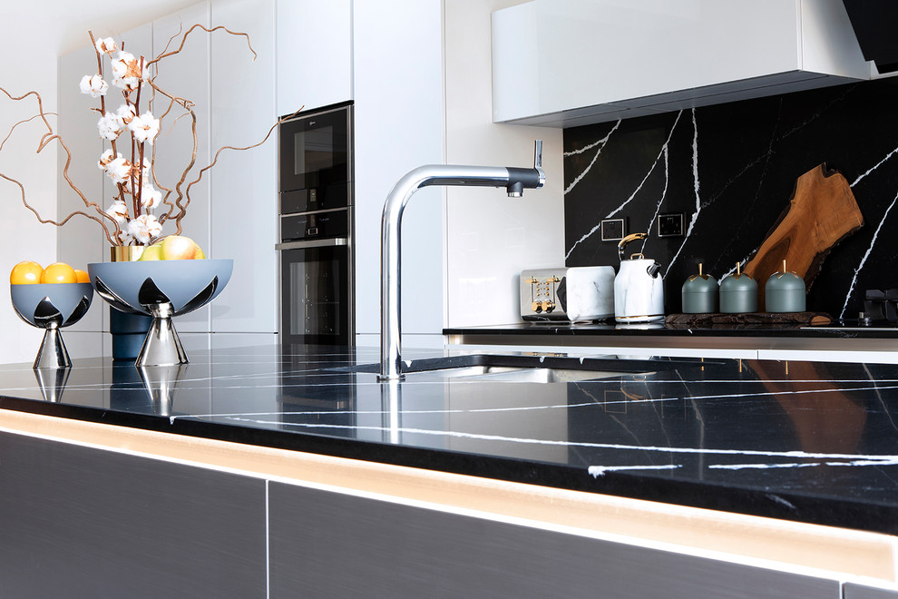 Exempel på ett stort modernt svart linjärt svart kök och matrum, med en undermonterad diskho, släta luckor, grå skåp, bänkskiva i kvarts, svart stänkskydd, stänkskydd i sten, svarta vitvaror, klinkergolv i keramik, en köksö och grått golv