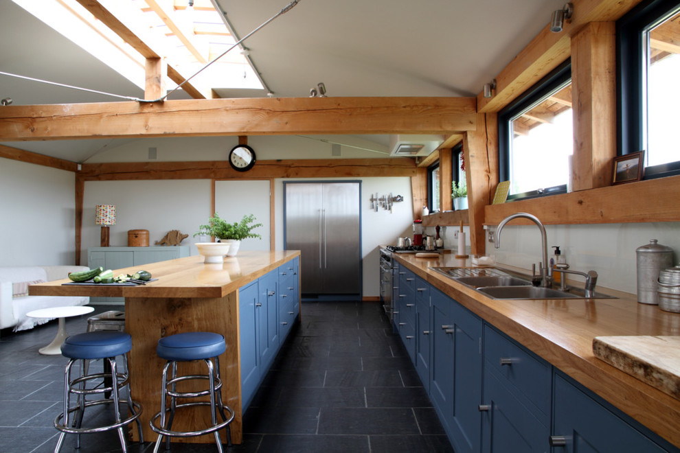 Esempio di una grande cucina minimalista con ante in stile shaker, top in legno, paraspruzzi con lastra di vetro, lavello integrato, ante blu e pavimento in ardesia