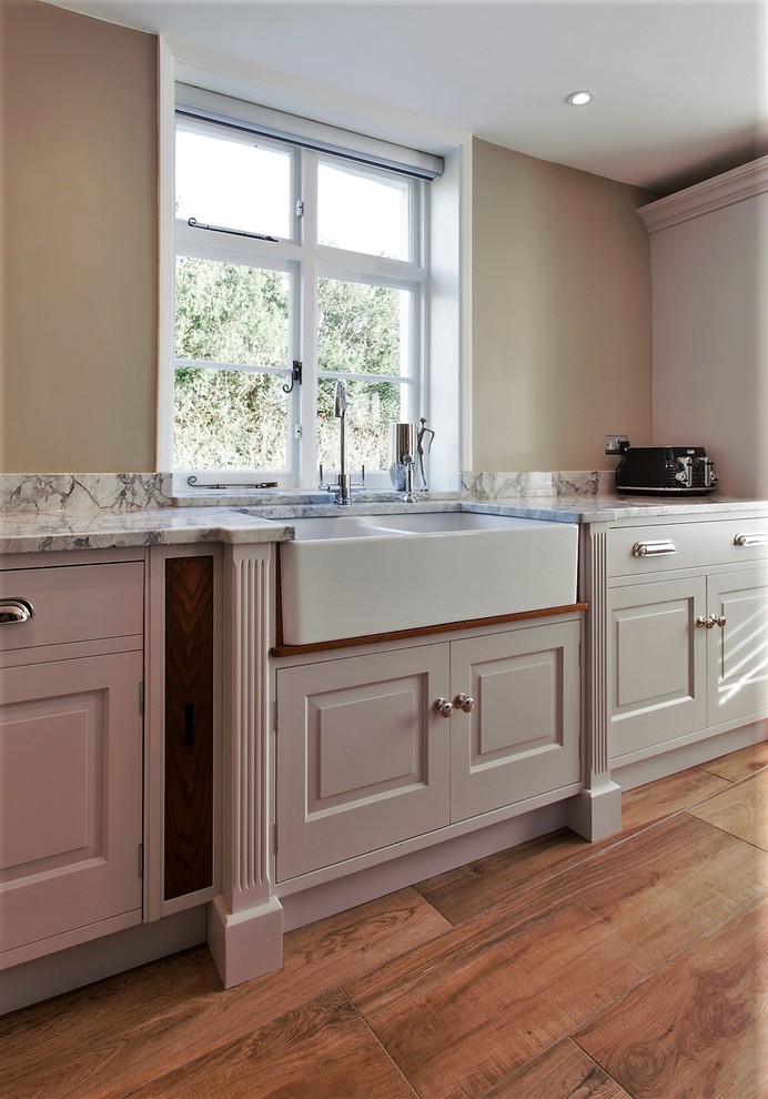 Immagine di una grande cucina abitabile classica con lavello stile country, top in granito e pavimento in legno massello medio