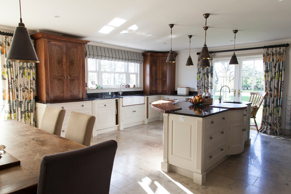 Inspiration for a large classic kitchen/diner in Essex with a belfast sink, dark wood cabinets, granite worktops, black splashback, limestone flooring and an island.