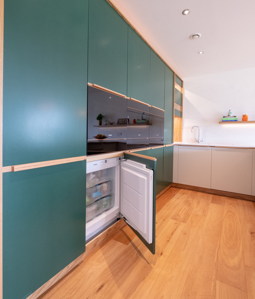 Modern inredning av ett mellanstort kök, med släta luckor, gröna skåp och en halv köksö
