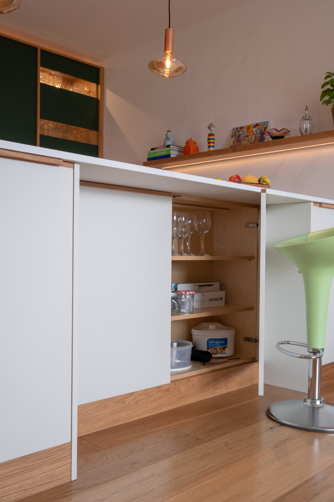 На фото: п-образная кухня среднего размера в современном стиле с обеденным столом, плоскими фасадами, зелеными фасадами и полуостровом
