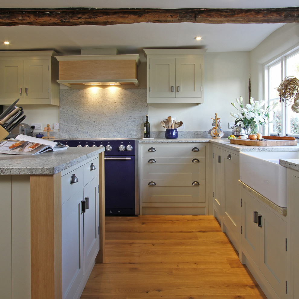 Design ideas for a country l-shaped kitchen in Hampshire with a belfast sink, granite worktops, shaker cabinets, beige cabinets, coloured appliances, white splashback and stone slab splashback.