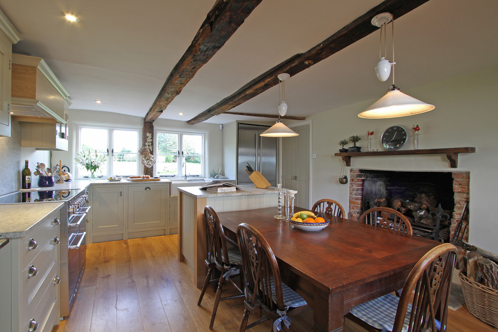 This is an example of a farmhouse l-shaped kitchen/diner in Hampshire with stainless steel appliances, shaker cabinets, beige cabinets and granite worktops.