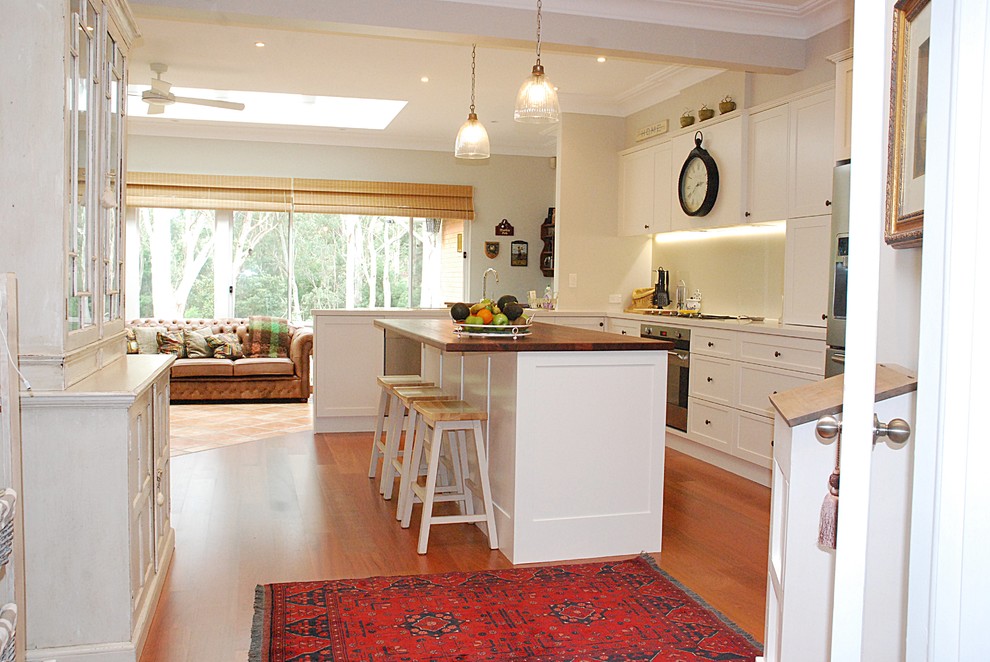 Eat-in kitchen - large traditional l-shaped medium tone wood floor eat-in kitchen idea in Sydney with a drop-in sink, shaker cabinets, white cabinets, quartz countertops, metallic backsplash, glass sheet backsplash, stainless steel appliances and an island