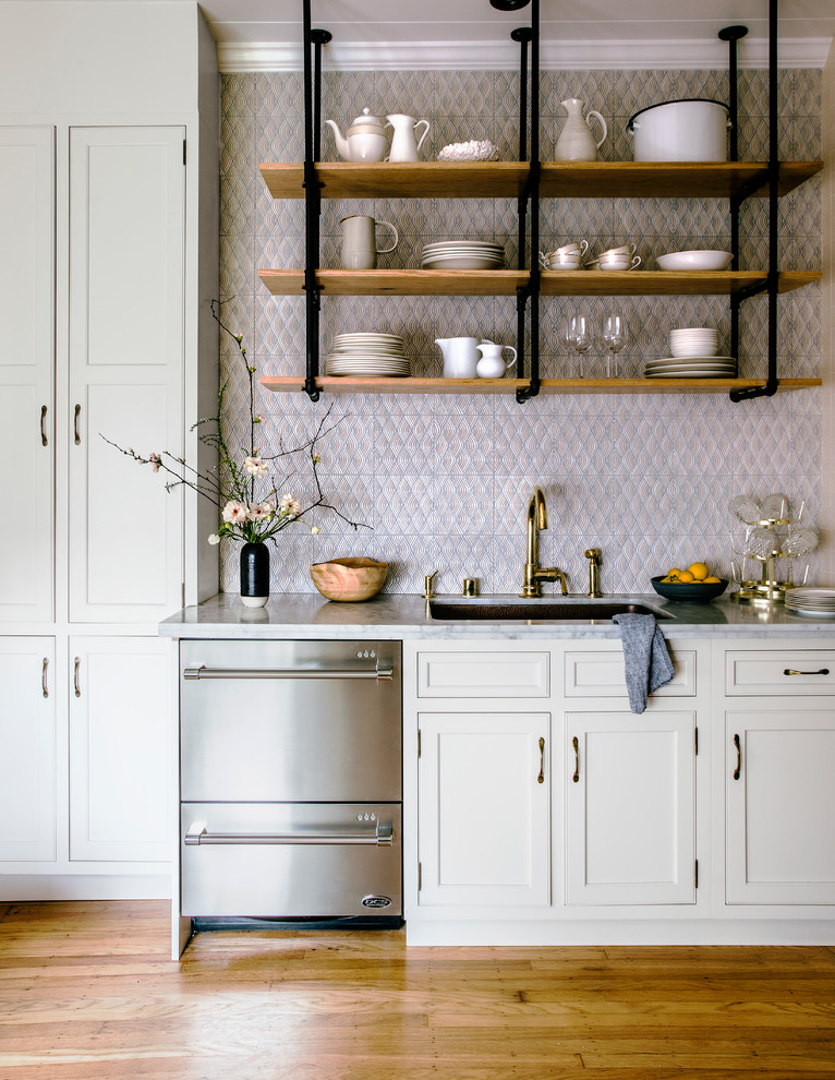 Imagen de cocina clásica con puertas de armario grises, encimera de mármol, salpicadero blanco, salpicadero de azulejos de cerámica y una isla