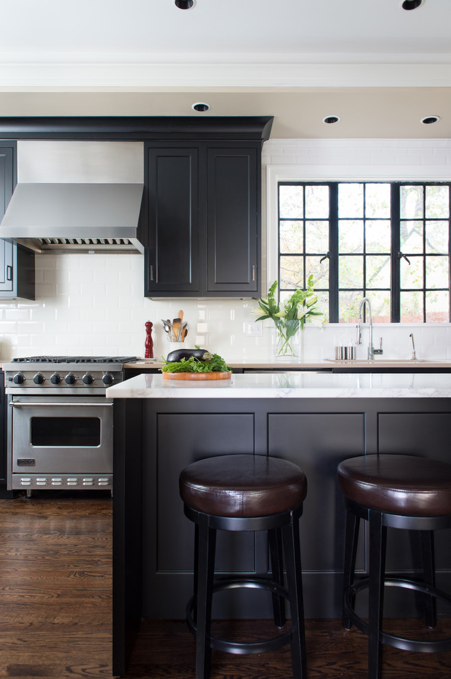 Klassische Küche mit Schrankfronten mit vertiefter Füllung, schwarzen Schränken, Küchenrückwand in Weiß, Rückwand aus Keramikfliesen, dunklem Holzboden und Kücheninsel in Kansas City