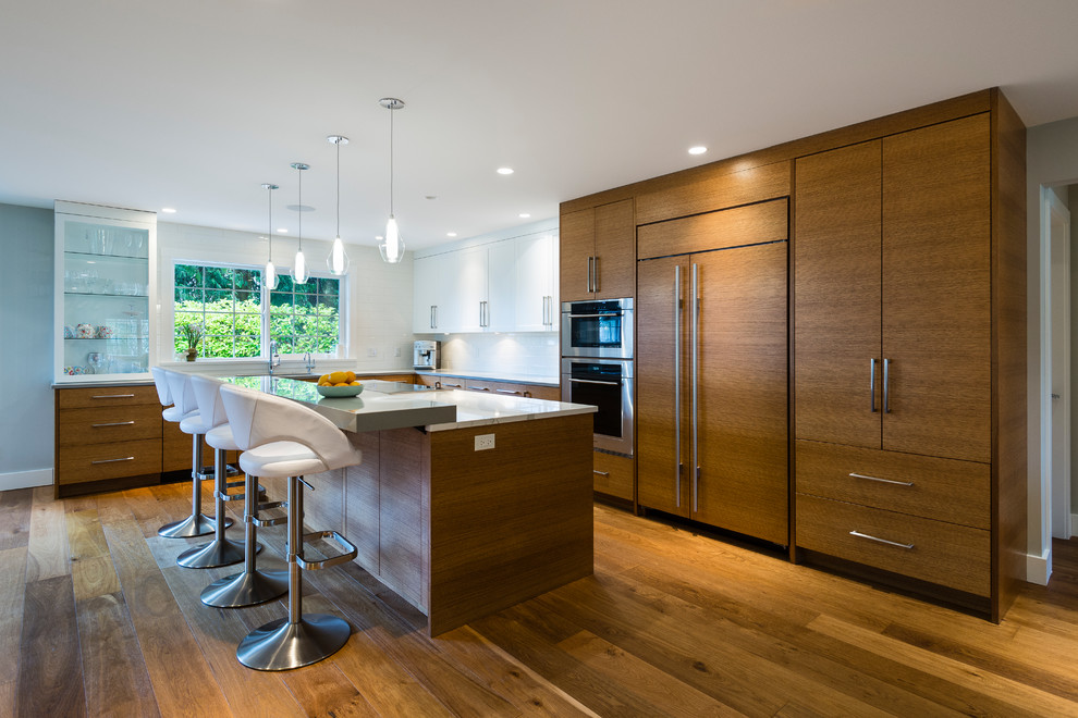 Inspiration for a large contemporary l-shaped medium tone wood floor open concept kitchen remodel in Vancouver with an undermount sink, flat-panel cabinets, medium tone wood cabinets, quartz countertops, white backsplash, subway tile backsplash, stainless steel appliances and an island