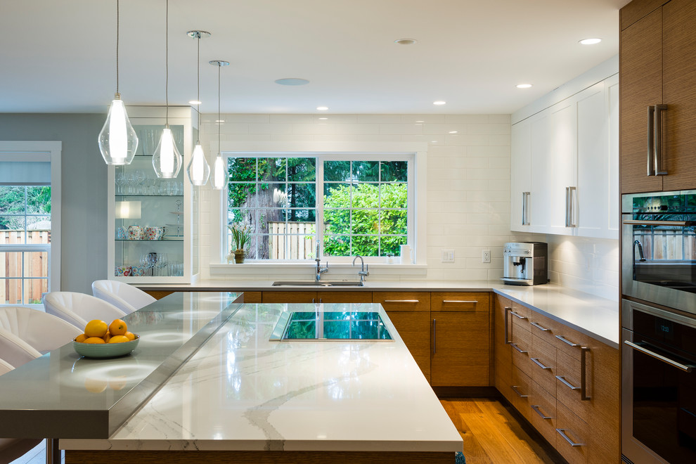Large trendy l-shaped medium tone wood floor open concept kitchen photo in Vancouver with an undermount sink, flat-panel cabinets, medium tone wood cabinets, quartz countertops, white backsplash, subway tile backsplash, stainless steel appliances and an island