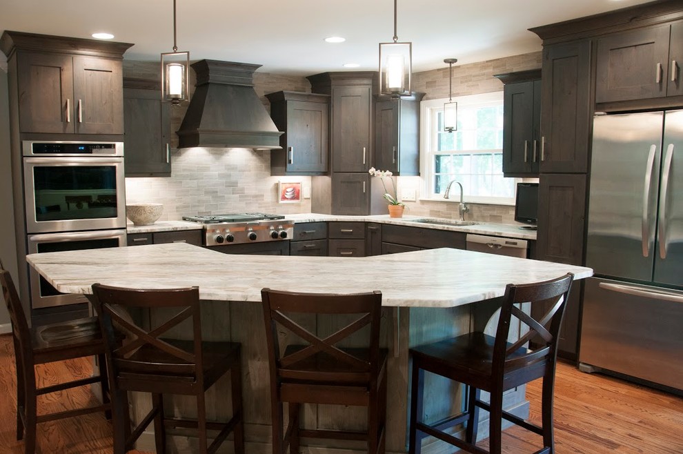 Example of a mid-sized transitional l-shaped medium tone wood floor eat-in kitchen design in Nashville with an undermount sink, shaker cabinets, dark wood cabinets, granite countertops, gray backsplash, stone tile backsplash, stainless steel appliances and an island