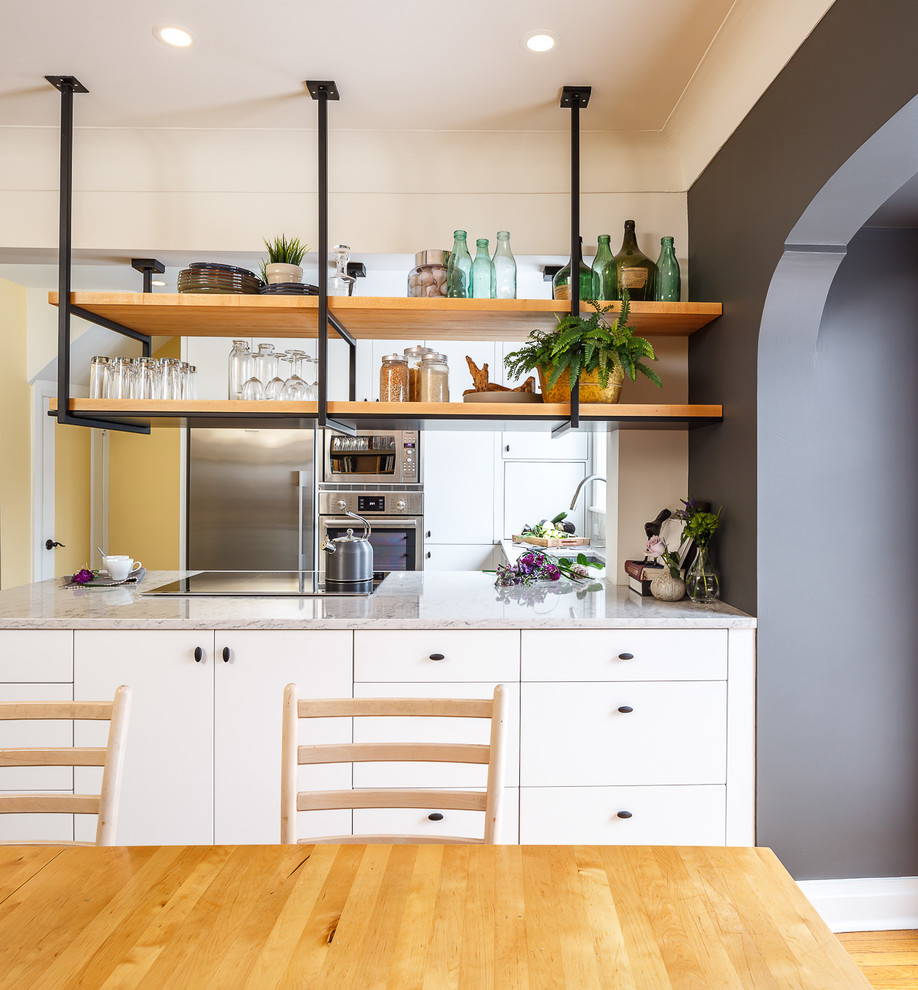 This is an example of a small industrial kitchen in Ottawa with flat-panel cabinets, white cabinets, granite worktops, white splashback, stainless steel appliances and an island.