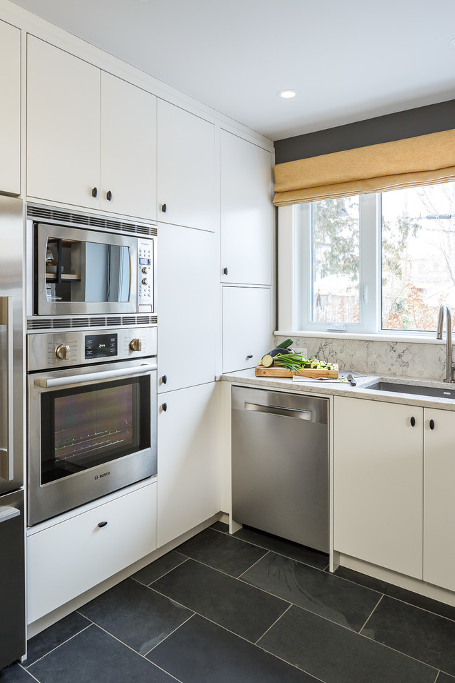 Foto de cocina urbana pequeña con armarios con paneles lisos, puertas de armario blancas, encimera de granito, salpicadero blanco, electrodomésticos de acero inoxidable y una isla