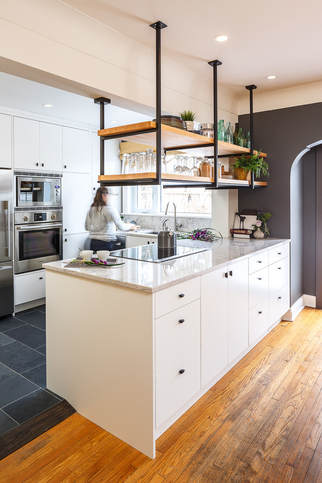 Kleine Industrial Küche mit flächenbündigen Schrankfronten, weißen Schränken, Granit-Arbeitsplatte, Küchenrückwand in Weiß, Küchengeräten aus Edelstahl und Kücheninsel in Ottawa