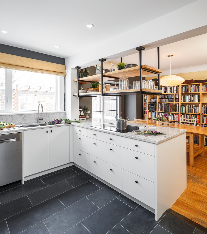 Inspiration for a mid-sized industrial l-shaped slate floor and gray floor eat-in kitchen remodel in Ottawa with flat-panel cabinets, white cabinets, granite countertops, white backsplash, stainless steel appliances, an island, an undermount sink and stone slab backsplash