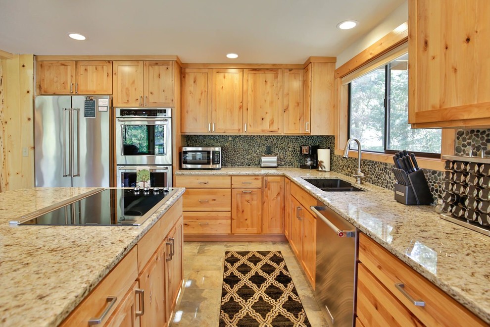 Foto på ett mellanstort rustikt kök, med en nedsänkt diskho, skåp i shakerstil, skåp i ljust trä, granitbänkskiva, beige stänkskydd, stänkskydd i sten, rostfria vitvaror, klinkergolv i porslin och en köksö