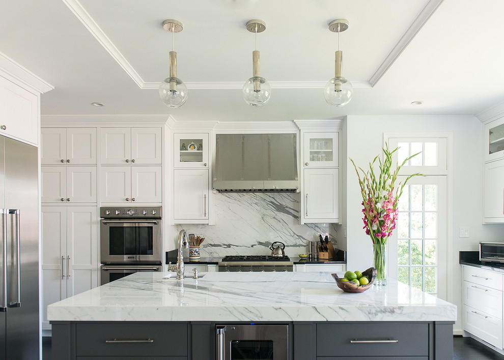 Inredning av ett klassiskt kök och matrum, med en undermonterad diskho, skåp i shakerstil, vita skåp, marmorbänkskiva, vitt stänkskydd, stänkskydd i sten, rostfria vitvaror, mörkt trägolv och en köksö