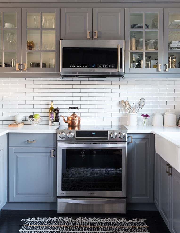 This is an example of a classic kitchen/diner in Los Angeles with glass-front cabinets, grey cabinets, white splashback and stainless steel appliances.