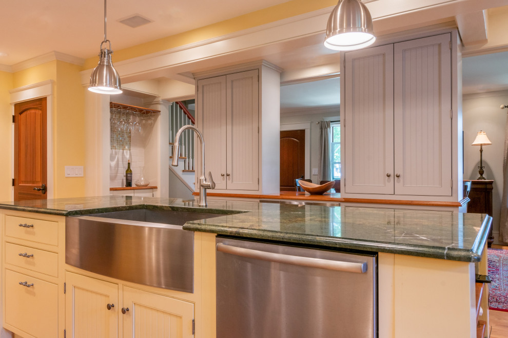 Exempel på ett avskilt, mellanstort lantligt grön grönt kök, med en rustik diskho, luckor med profilerade fronter, gula skåp, granitbänkskiva, vitt stänkskydd, stänkskydd i tunnelbanekakel, rostfria vitvaror, ljust trägolv, en köksö och brunt golv