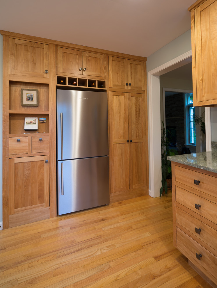 Example of a mid-sized classic u-shaped light wood floor eat-in kitchen design in Burlington with an undermount sink, recessed-panel cabinets, light wood cabinets, granite countertops, stainless steel appliances and a peninsula
