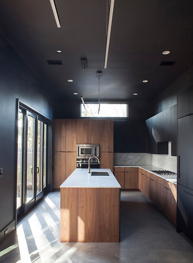 Immagine di una cucina moderna con lavello sottopiano, ante lisce, ante nere, top in marmo, paraspruzzi bianco, paraspruzzi in marmo, elettrodomestici in acciaio inossidabile, pavimento in cemento e top bianco