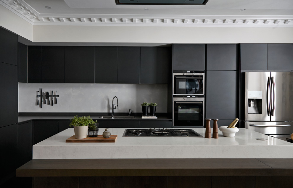 Стильный дизайн: угловая кухня в современном стиле с двойной мойкой, плоскими фасадами, черными фасадами, серым фартуком, техникой из нержавеющей стали, островом и барной стойкой - последний тренд
