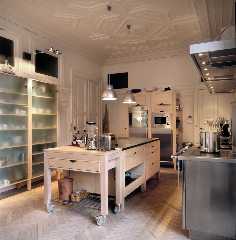 Immagine di una cucina industriale chiusa con ante in stile shaker, ante in legno chiaro, top in granito, elettrodomestici in acciaio inossidabile e parquet chiaro
