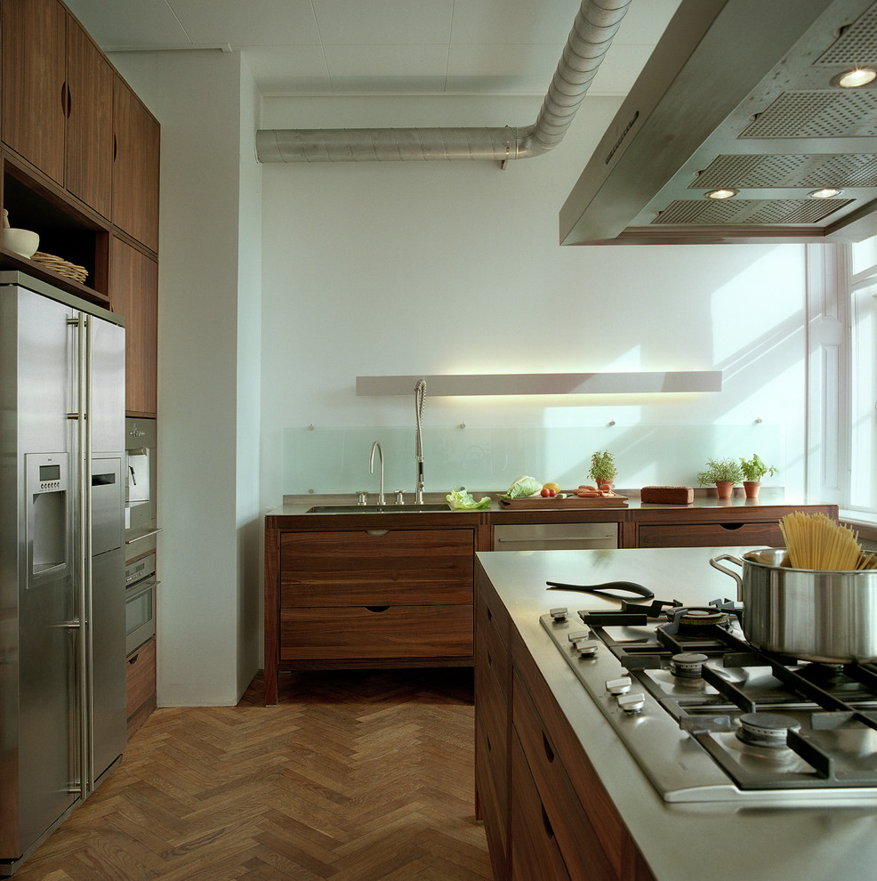 Industrial Küche in U-Form mit flächenbündigen Schrankfronten, dunklen Holzschränken, Küchengeräten aus Edelstahl, braunem Holzboden und Kücheninsel in Kopenhagen