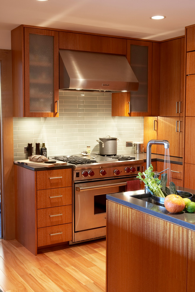 Foto på ett mellanstort funkis kök, med en nedsänkt diskho, släta luckor, skåp i mellenmörkt trä, bänkskiva i kvarts, svart stänkskydd, rostfria vitvaror, mellanmörkt trägolv och en köksö