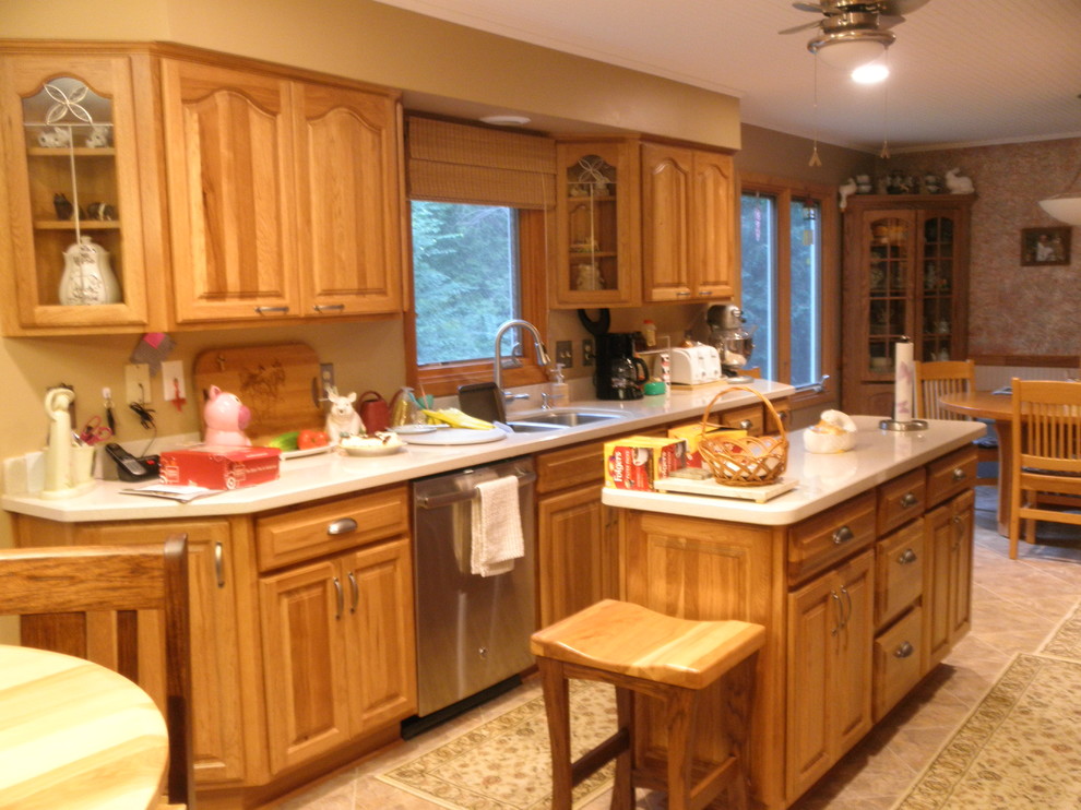 Exempel på ett mellanstort klassiskt kök, med en undermonterad diskho, luckor med upphöjd panel, skåp i ljust trä, bänkskiva i kvarts, rostfria vitvaror, klinkergolv i keramik och en köksö