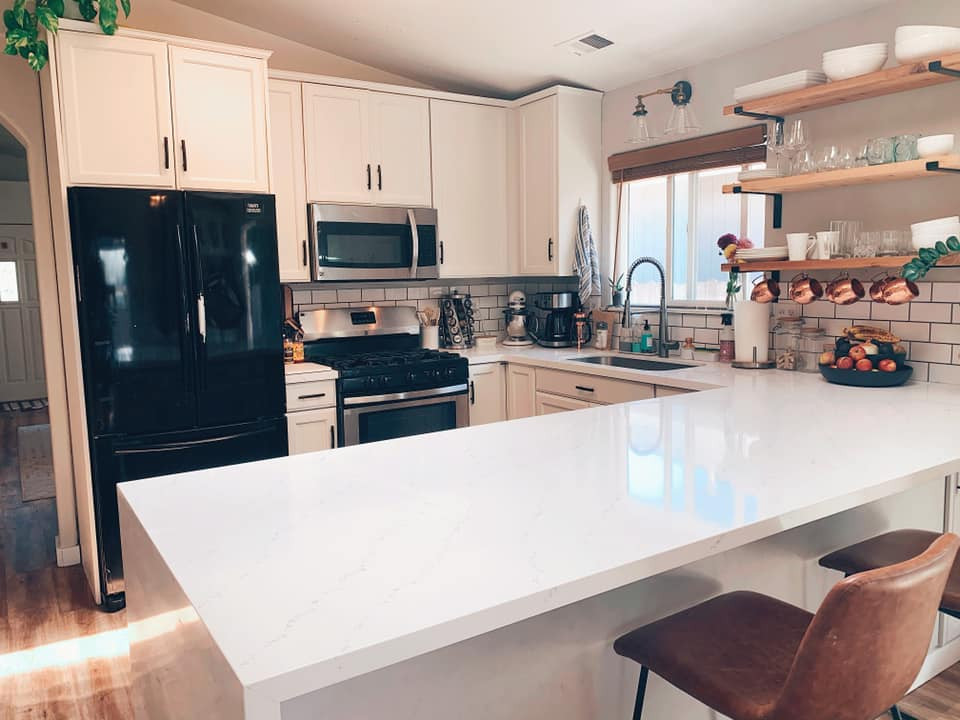 Mid-sized minimalist l-shaped eat-in kitchen photo in Other with a single-bowl sink, white cabinets, quartz countertops, white backsplash, stainless steel appliances and white countertops