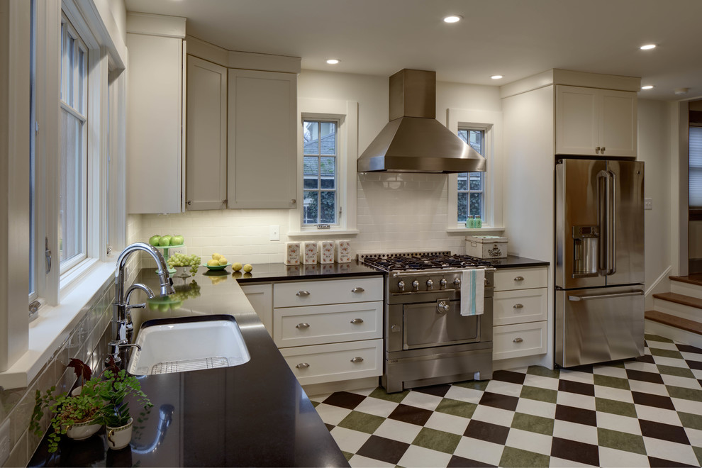 Example of a mid-sized transitional l-shaped linoleum floor enclosed kitchen design in New York with an undermount sink, shaker cabinets, white cabinets, quartz countertops, white backsplash, ceramic backsplash, stainless steel appliances and no island