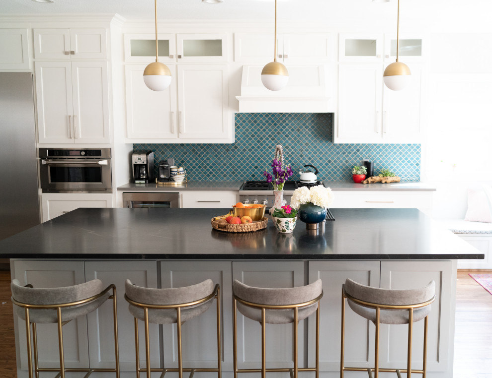 Immagine di un cucina con isola centrale classico con lavello da incasso, ante di vetro, ante bianche, paraspruzzi blu, elettrodomestici in acciaio inossidabile, parquet scuro, pavimento marrone e top nero