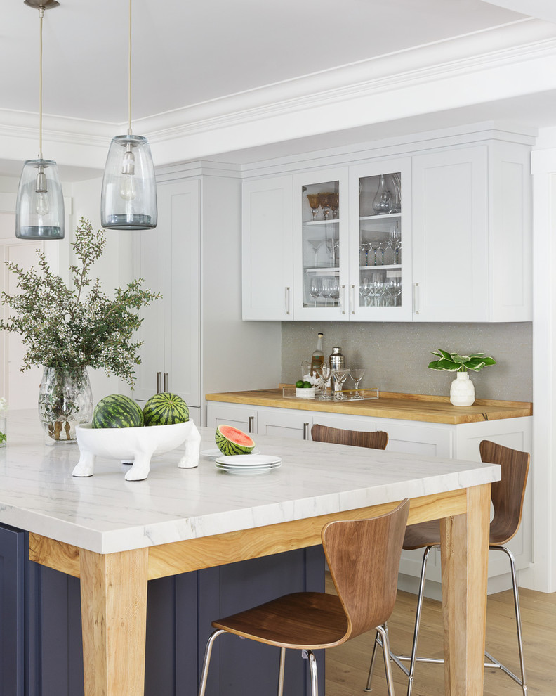 Inspiration for a large traditional l-shaped open plan kitchen in San Francisco with a single-bowl sink, shaker cabinets, white cabinets, marble worktops, grey splashback, integrated appliances, light hardwood flooring, an island and brown floors.