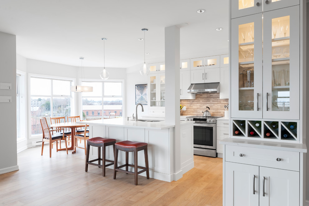 Medium sized traditional l-shaped kitchen/diner in Vancouver with a submerged sink, shaker cabinets, white cabinets, engineered stone countertops, grey splashback, glass tiled splashback, stainless steel appliances, laminate floors and an island.