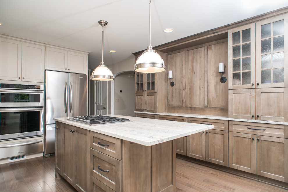 Photo of a large classic l-shaped open plan kitchen in Detroit with a submerged sink, shaker cabinets, grey cabinets, granite worktops, white splashback, metro tiled splashback, stainless steel appliances, light hardwood flooring, an island and beige floors.
