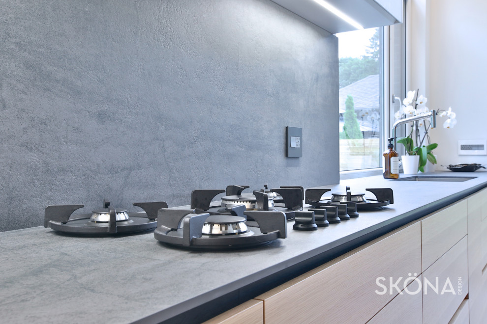 Immagine di una cucina minimal di medie dimensioni con lavello sottopiano, ante lisce, ante grigie, top in quarzo composito, paraspruzzi grigio, paraspruzzi in lastra di pietra, elettrodomestici in acciaio inossidabile e top grigio