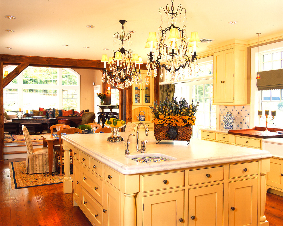 Example of a large classic medium tone wood floor kitchen design in New York with wood countertops, white backsplash, an island and recessed-panel cabinets