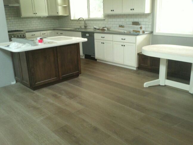 Example of a mid-sized classic l-shaped light wood floor and brown floor eat-in kitchen design in San Francisco with a drop-in sink, flat-panel cabinets, white cabinets, granite countertops, white backsplash, porcelain backsplash, white appliances and an island