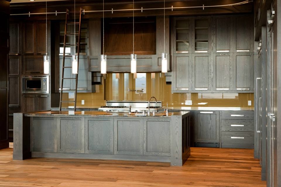 This is an example of a large traditional l-shaped kitchen in Calgary with a submerged sink, shaker cabinets, dark wood cabinets, granite worktops, brown splashback, glass sheet splashback, integrated appliances, medium hardwood flooring, an island and brown floors.