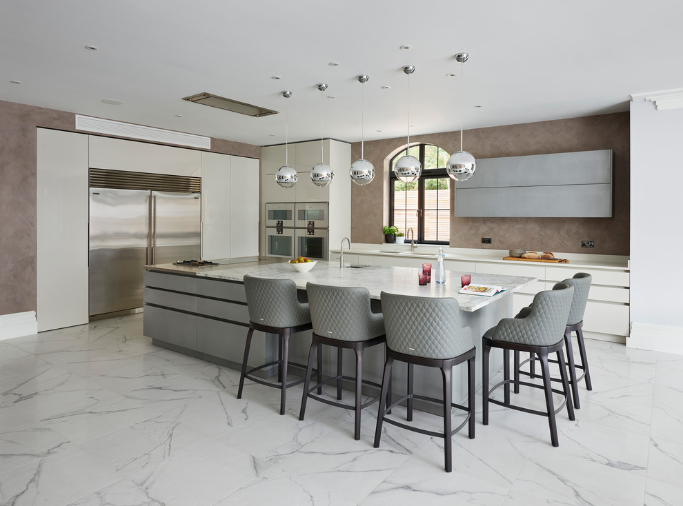 Modern inredning av ett mycket stort vit vitt kök med öppen planlösning, med släta luckor, vita skåp, granitbänkskiva och en köksö
