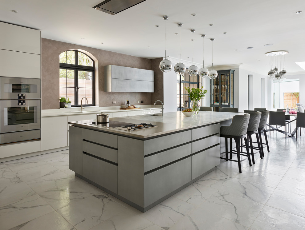 Design ideas for an expansive contemporary open plan kitchen in London with flat-panel cabinets, white cabinets, granite worktops, an island, white worktops and white floors.