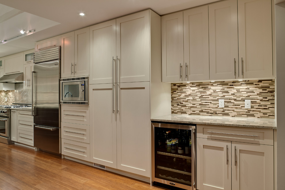 Photo of a large contemporary l-shaped kitchen/diner in Vancouver with a submerged sink, shaker cabinets, white cabinets, granite worktops, multi-coloured splashback, stainless steel appliances, medium hardwood flooring, an island and mosaic tiled splashback.
