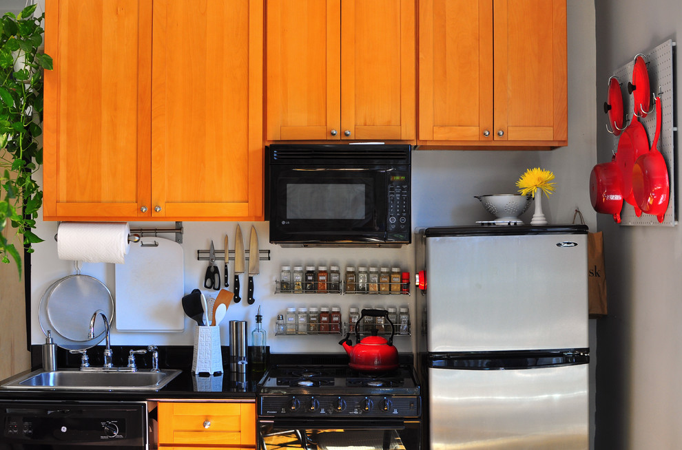ニューヨークにあるエクレクティックスタイルのおしゃれなI型キッチン (ドロップインシンク、シェーカースタイル扉のキャビネット、中間色木目調キャビネット、黒い調理設備) の写真