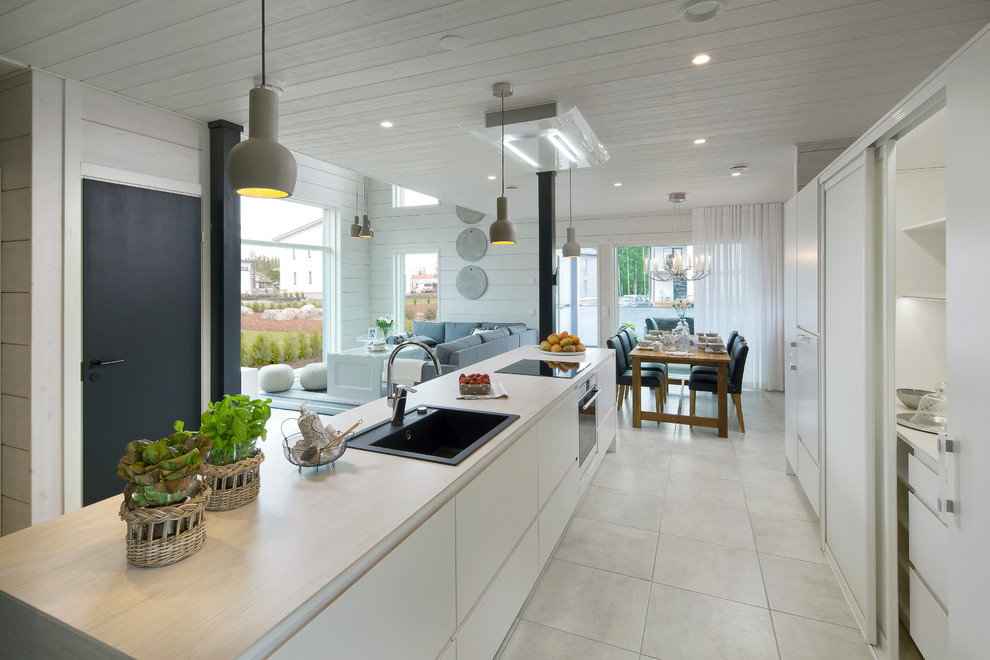 Imagen de cocina rectangular nórdica abierta con fregadero encastrado, armarios con paneles lisos, puertas de armario blancas y una isla